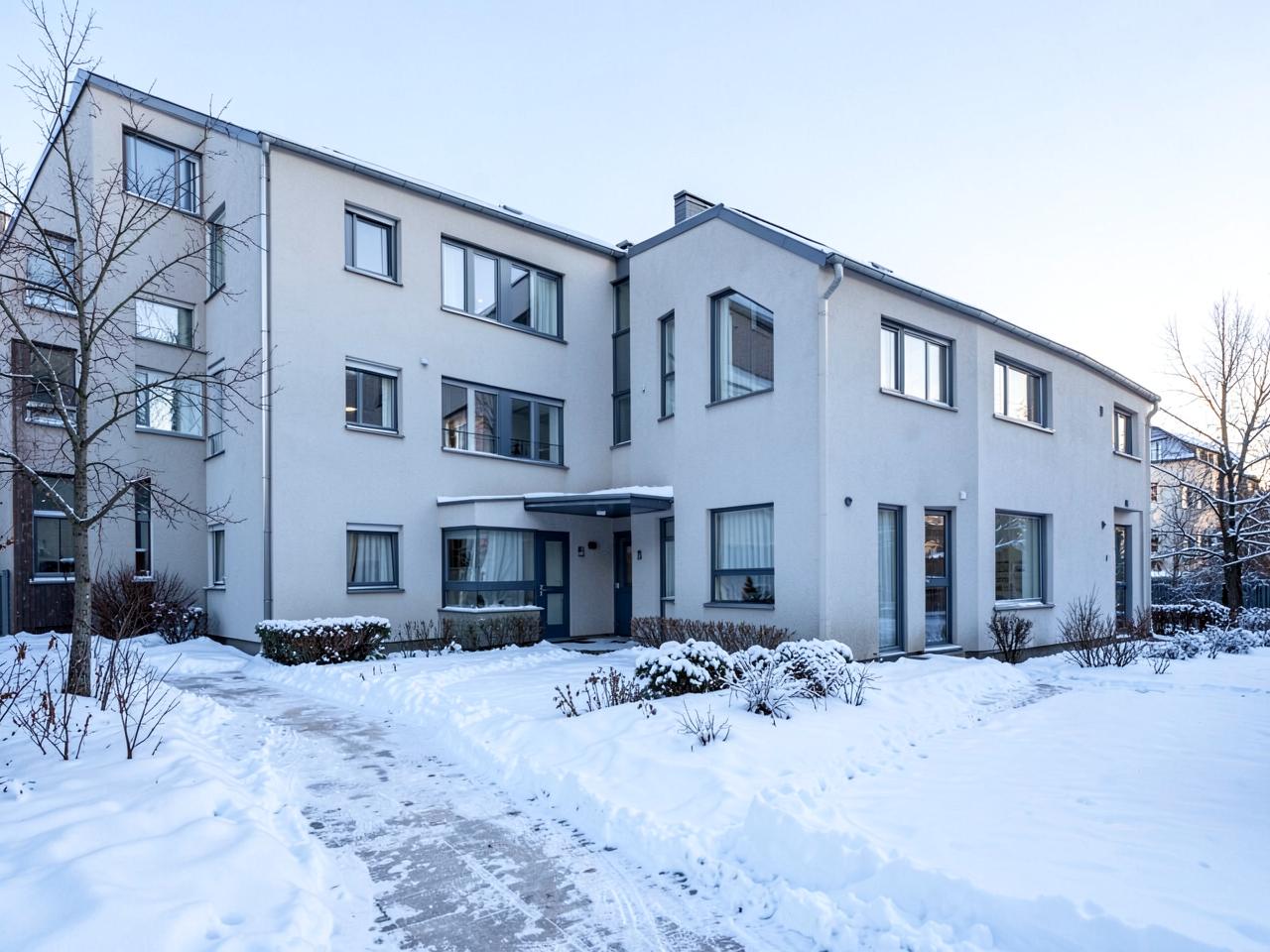 Taloyhtiön kerrostalo talvella hoidetulla pihalla